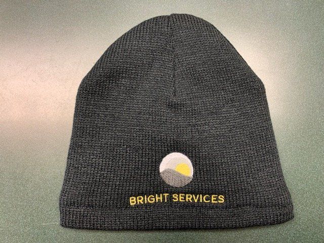 A black beanie that says bright services on it
