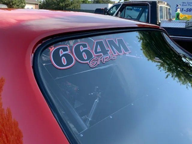 A red car with the number 664m on the windshield