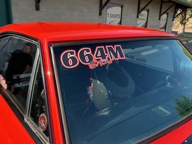 A red car with the number 664m on the windshield