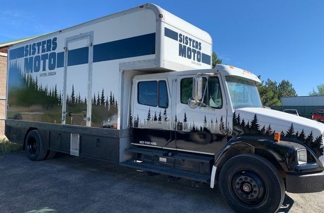 A white truck with the words sisters motor on the side is parked in a parking lot.