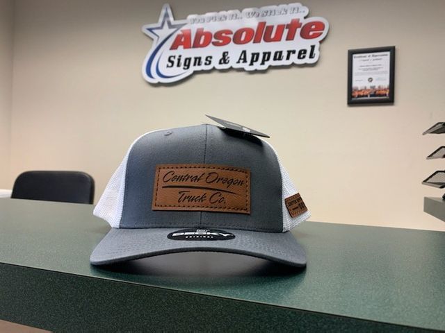 A hat is sitting on a counter in front of absolute signs and apparel