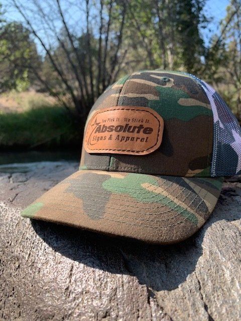 A camouflage baseball cap is sitting on top of a rock.
