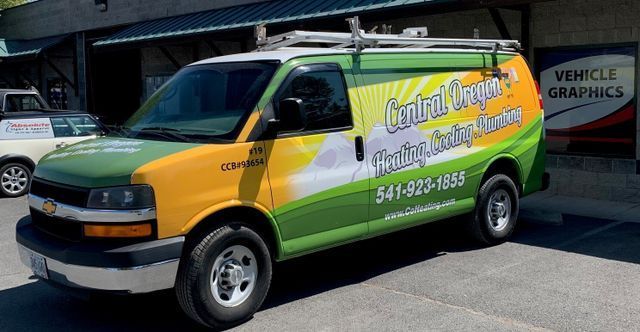 A green and yellow van is parked in front of a building.