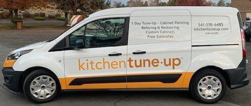 A white and yellow van is parked in a parking lot.