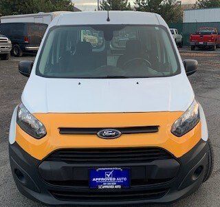 A yellow and white ford transit connect van is parked in a parking lot.