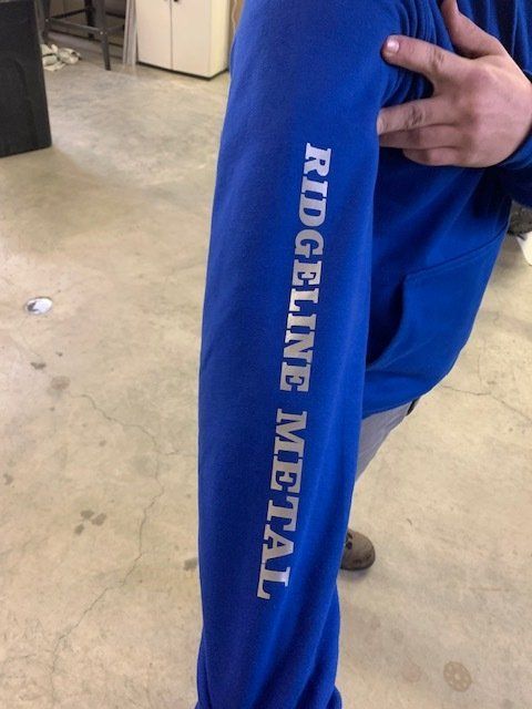 A person wearing a blue shirt that says ridgeline metal