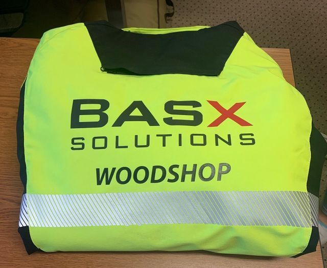A yellow vest that says basx solutions woodshop on it