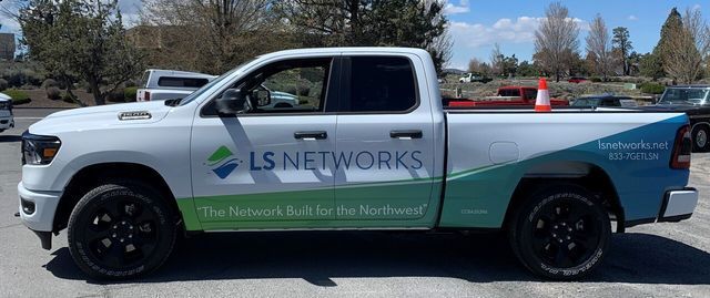 A white truck with ls networks written on the side is parked in a parking lot.