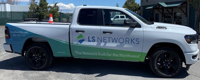 A white truck with ls networks written on the side is parked in a parking lot.