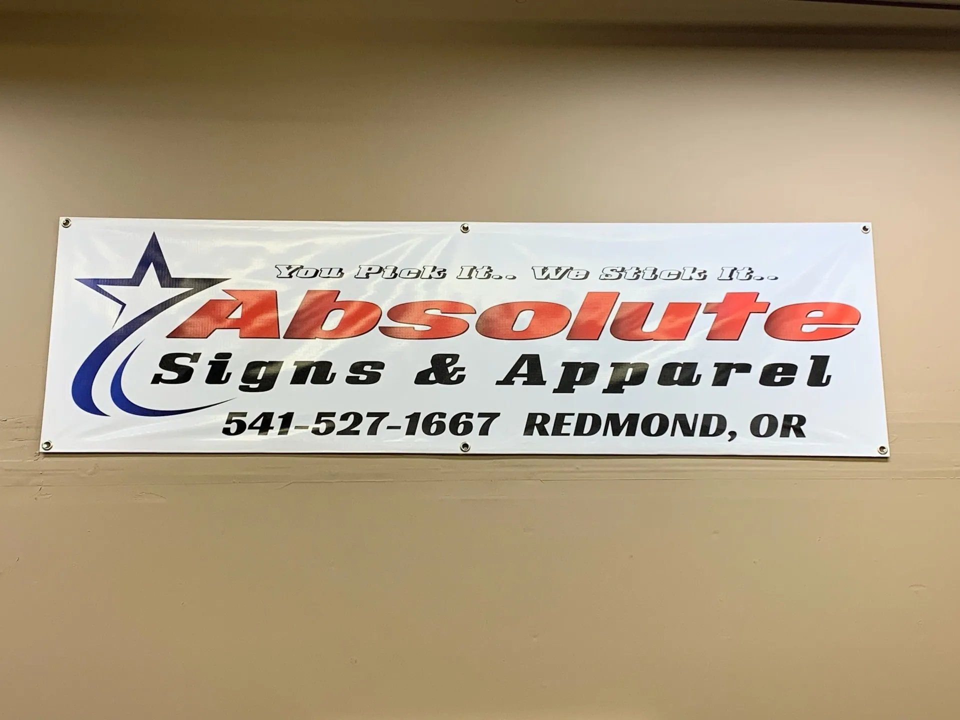 A sign for absolute signs and apparel hangs on a wall