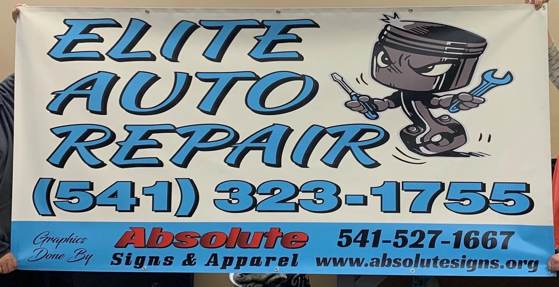 A man is holding a banner for elite auto repair