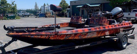 A fishing boat is parked on a trailer in a parking lot.