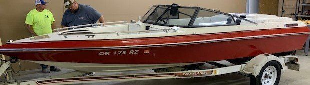 A red and white boat is on a trailer in a garage.