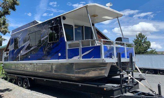 A blue and silver pontoon boat is parked on a trailer.
