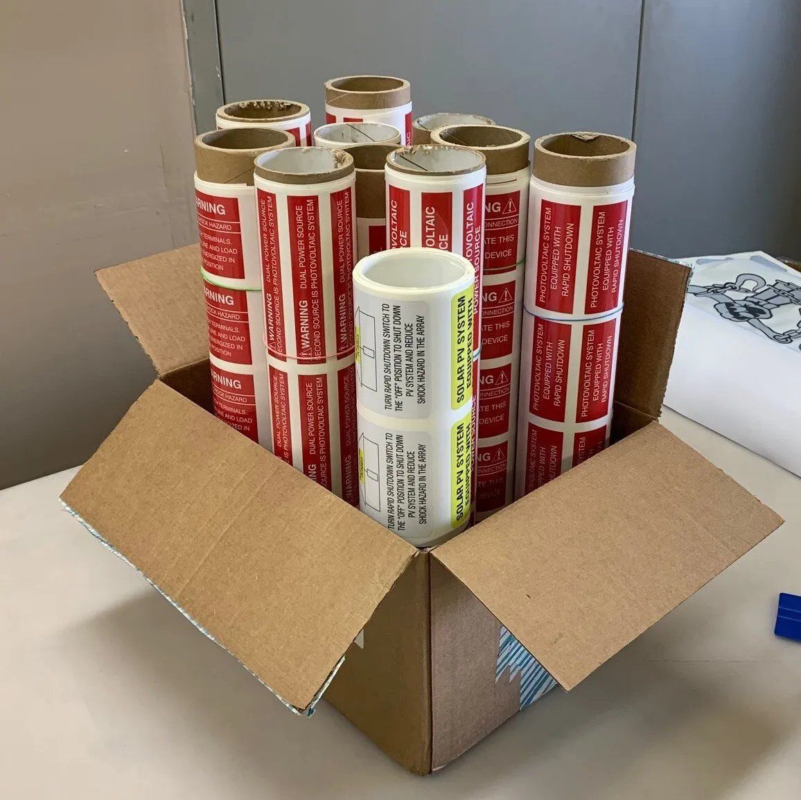 A cardboard box filled with rolls of red and white stickers