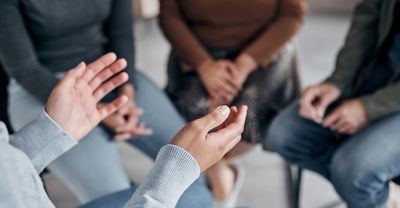 A group of people are sitting in a circle talking to each other.