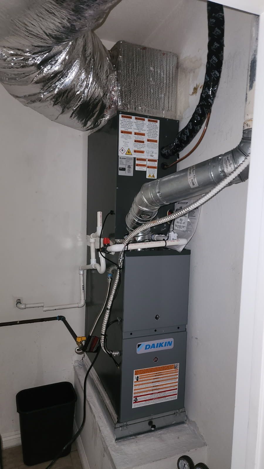 Air-source heat pump outside a building, on a concrete pad with dark supports.