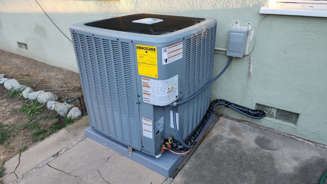 White ductless air conditioner mounted on a white wall in a room.