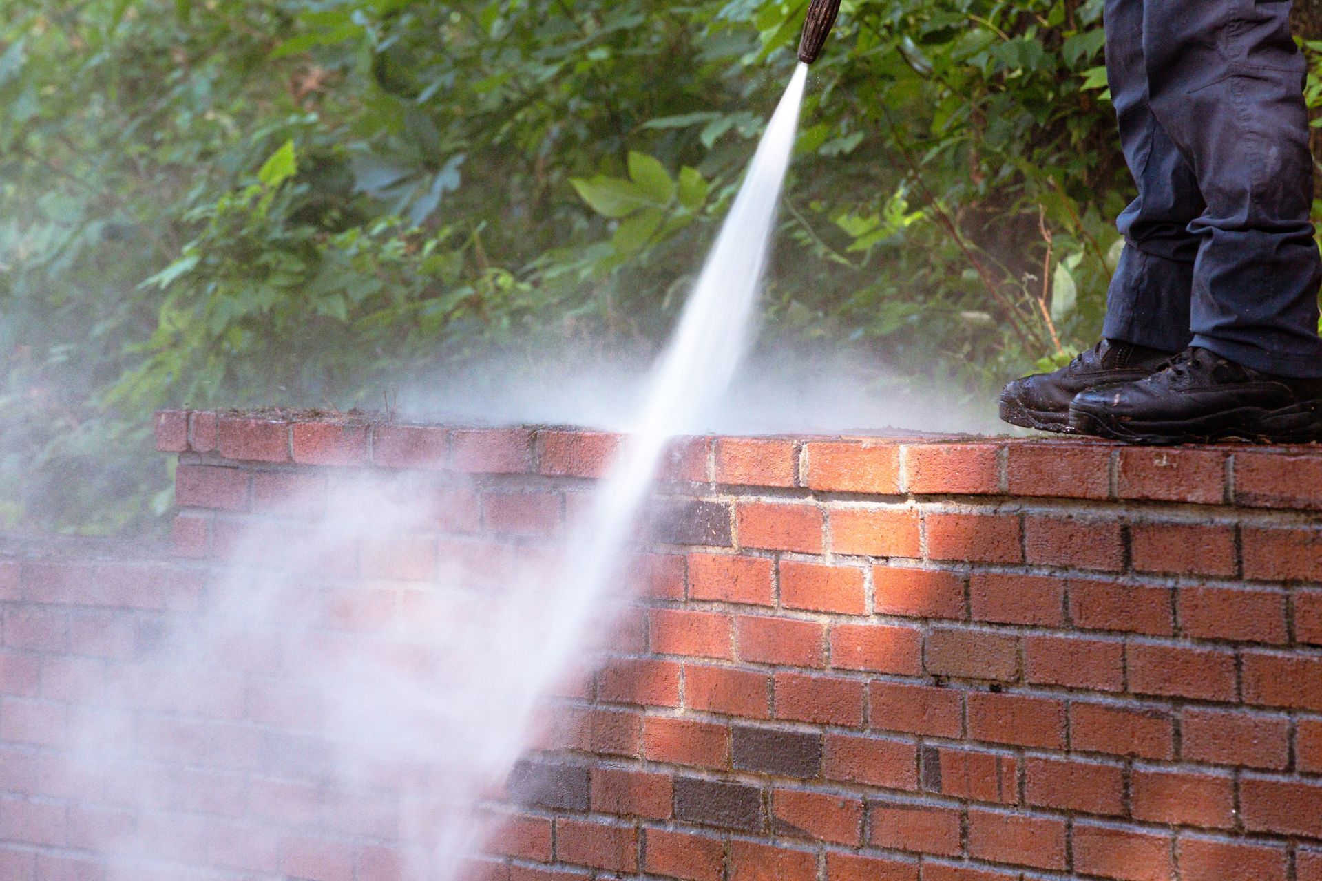 Power washing brick exterior wall of a house using high-pressure water spray Power washing brick exterior wall of a house using high-pressure water spray