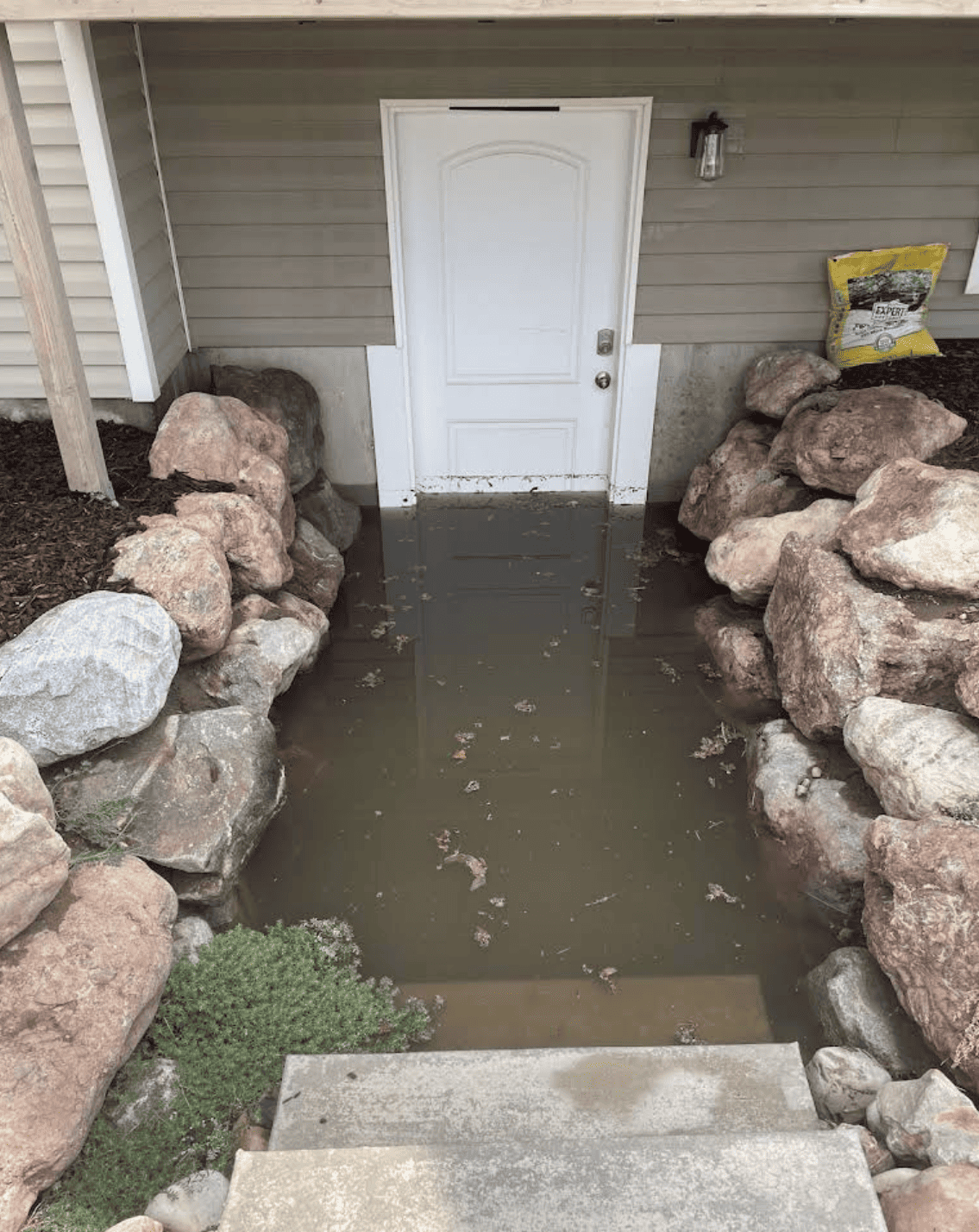 Flooded walkout basement entrance with water pooling at door