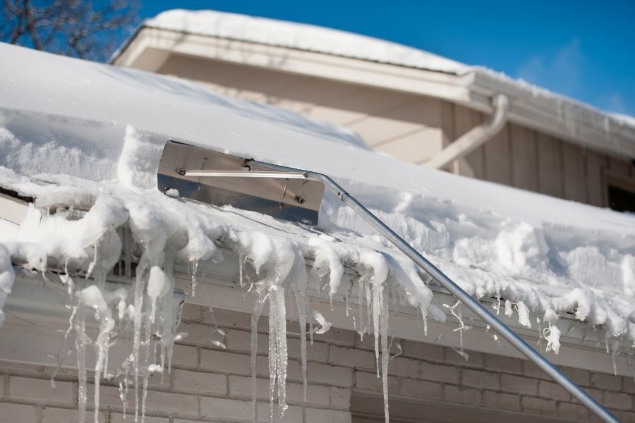 Using a roof rake to remove snow from roof