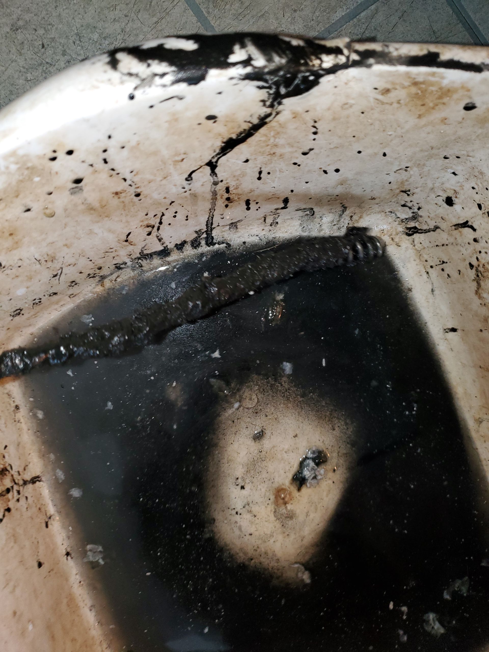 Cracked, white plastic object with a black, burnt-looking area and black streaks.