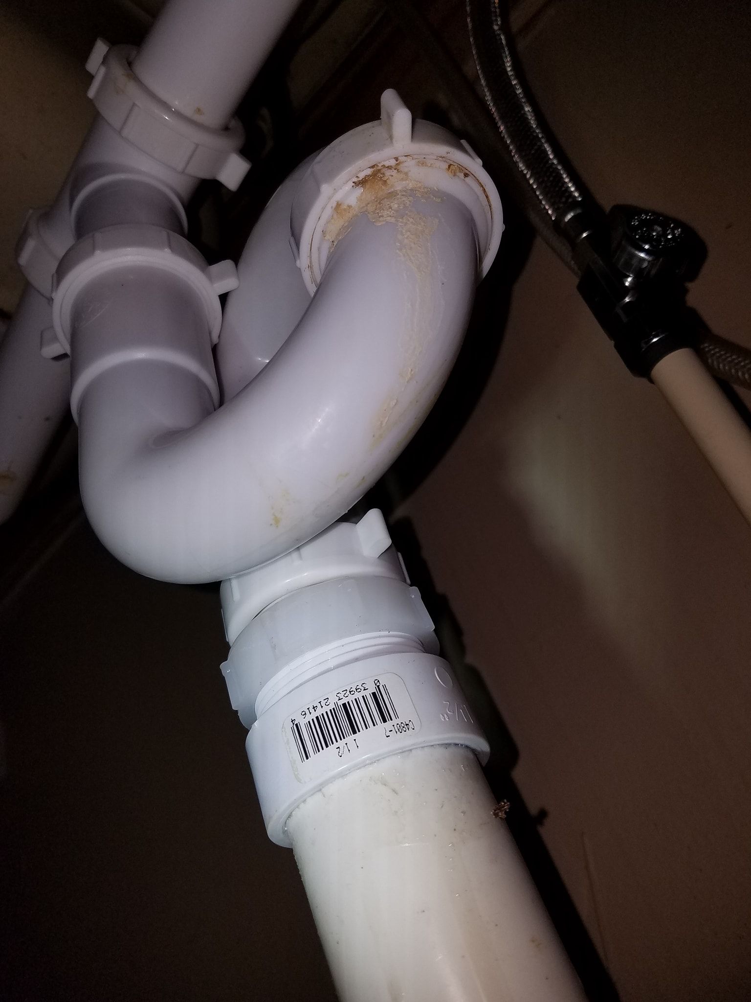 White plumbing pipes under a sink, including a U-shaped trap and connecting pipes, with clamp rings.