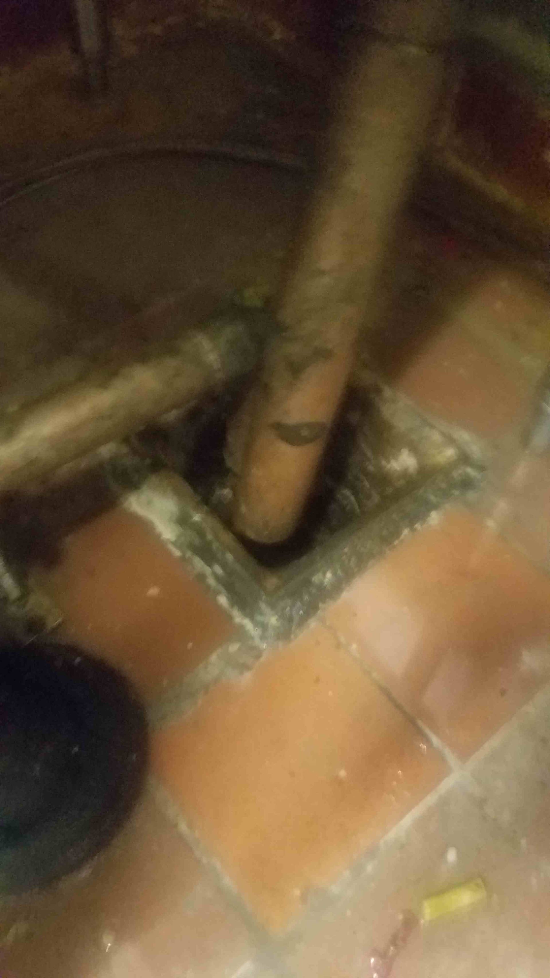 Tiled floor with a drain and pipes, close-up view.