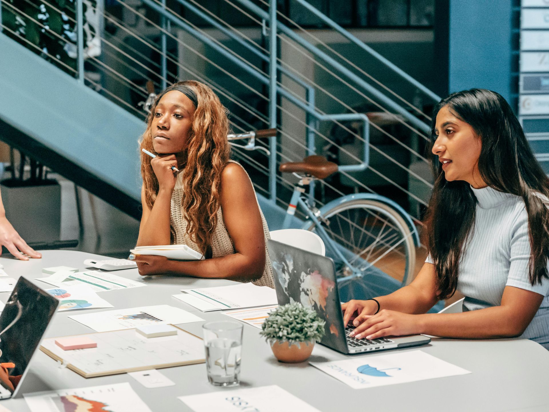 Three women are sitting at a table with laptops.