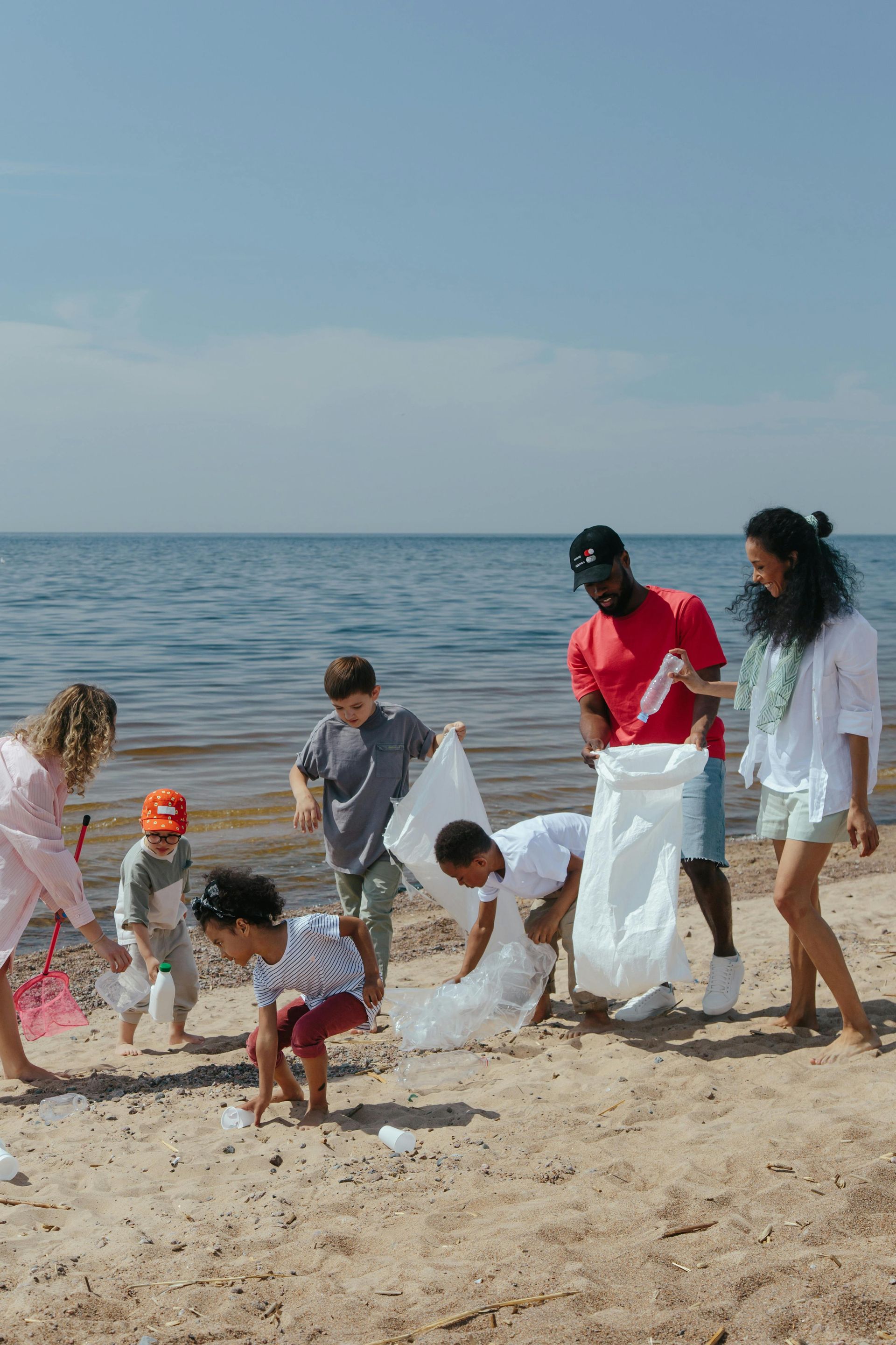 A group of people are picking up trash on the beach.