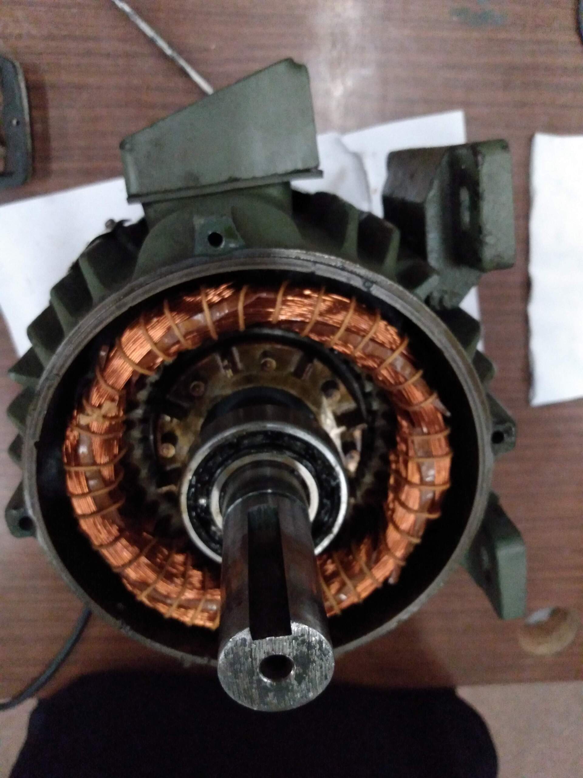Extremo abierto de un motor eléctrico que muestra los devanados de alambre de cobre y un eje metálico central con una chaveta.