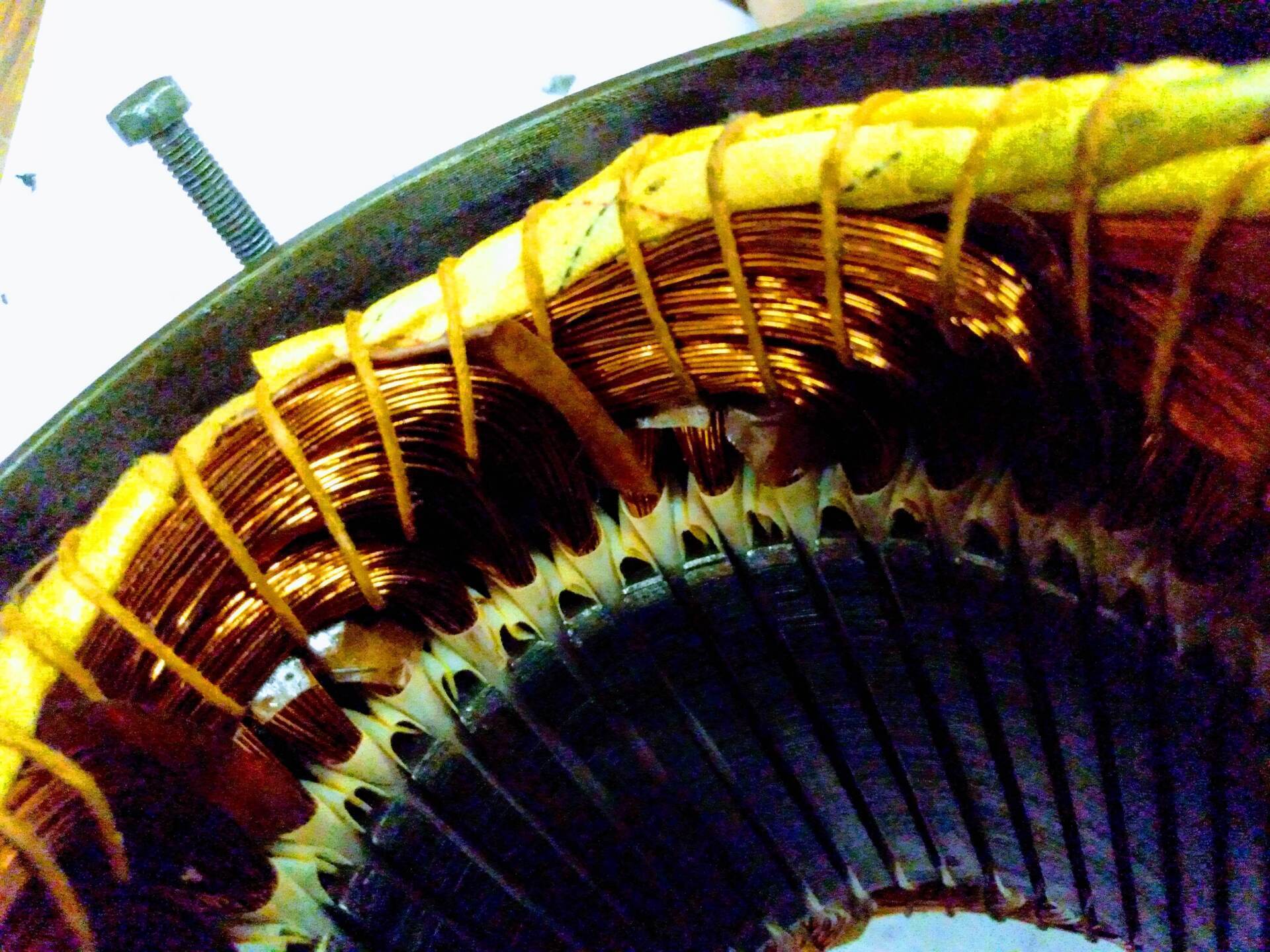 Primer plano de los devanados de alambre de cobre y el aislamiento de un motor eléctrico dentro de una carcasa metálica del estator.