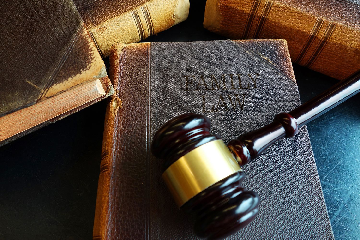 A judge’s gavel resting on a worn family law book surrounded by stacked legal volumes.