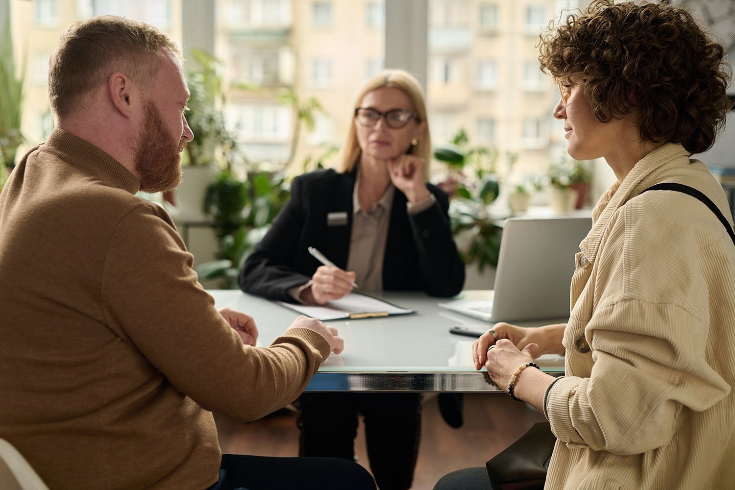 Couple meeting with a professional at a desk to review documents in a bright office setting. Couple meeting with a professional at a desk to review documents in a bright office setting.