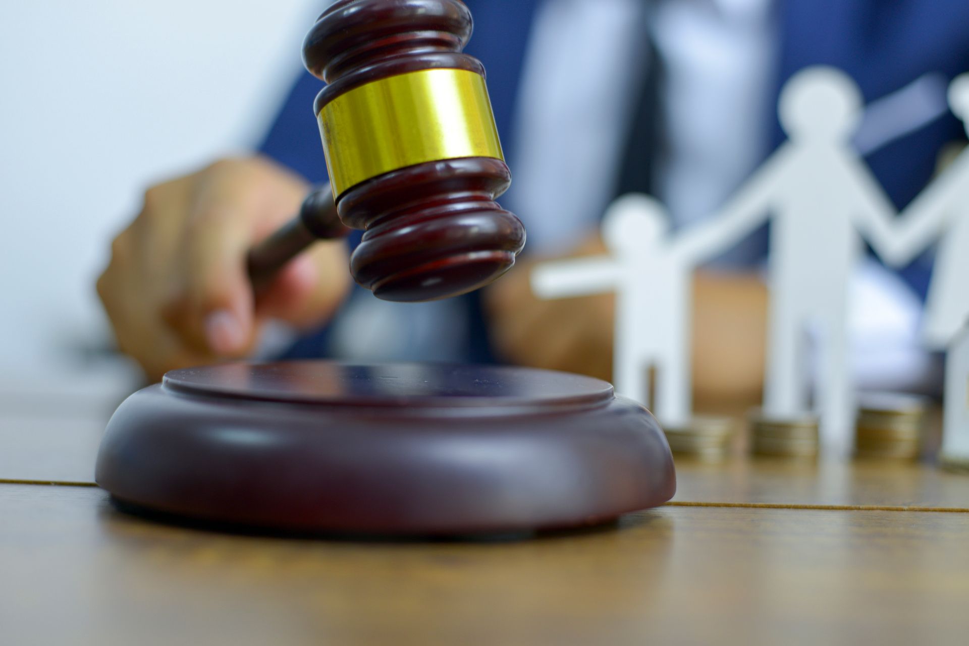 A family attorney in a blue suit holds a gavel on a table, with a family figure in the background.