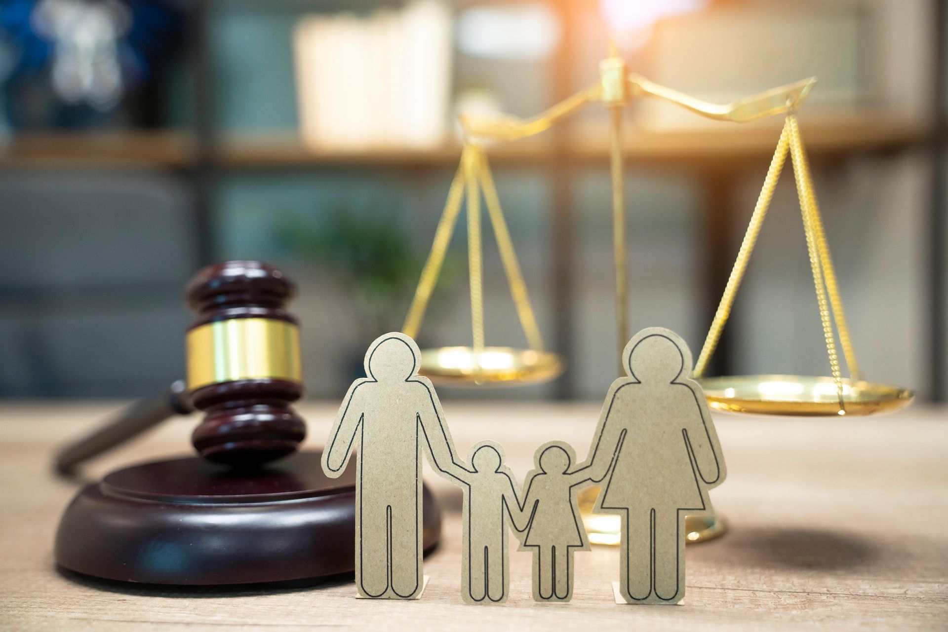 View of a family figure, wooden gavel, and a gold scale on a table of a family attorney.