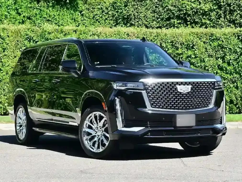 A black cadillac escalade is parked on the side of the road.