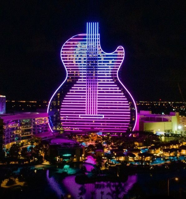 A building that looks like a guitar is lit up at night
