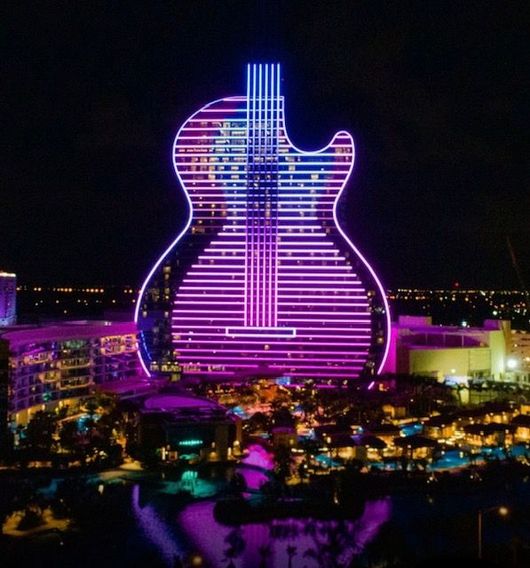 A building that looks like a guitar is lit up at night