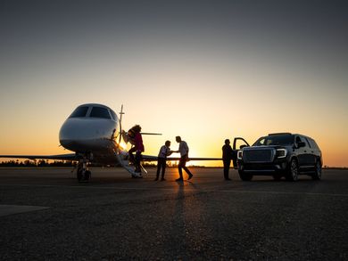 A group of people are standing next to a private jet on a runway.