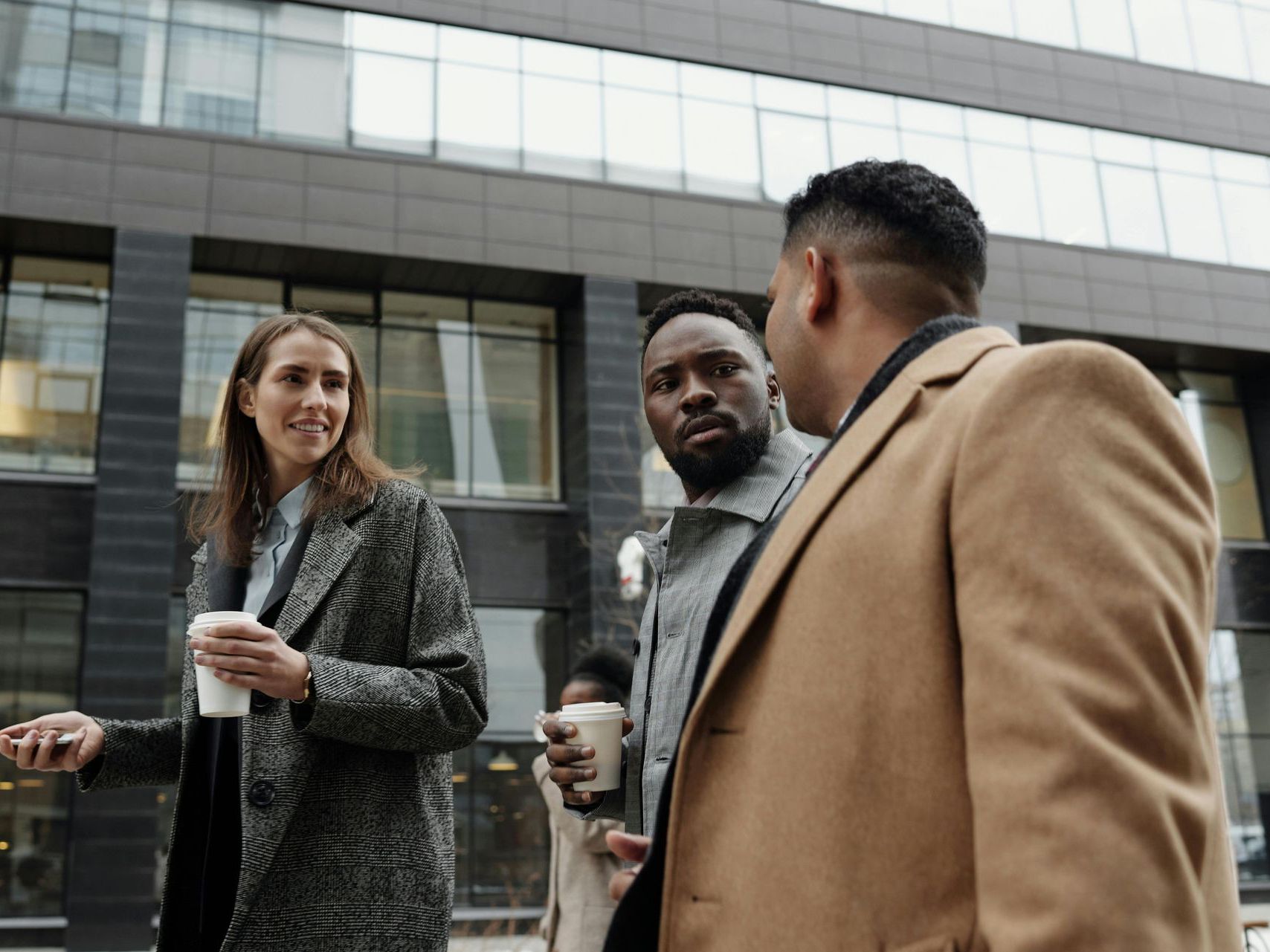 A group of people are standing in front of a building talking to each other.