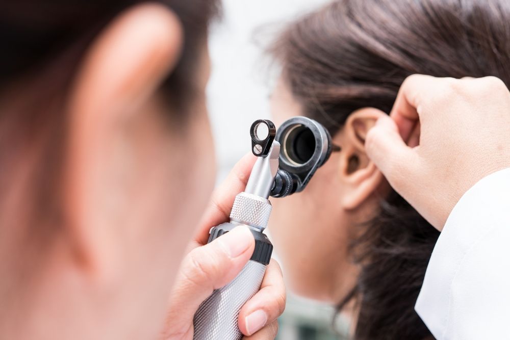A Doctor is Examining a Woman's Ear With a Tool — Clayton Hearing in Pialba, QLD
