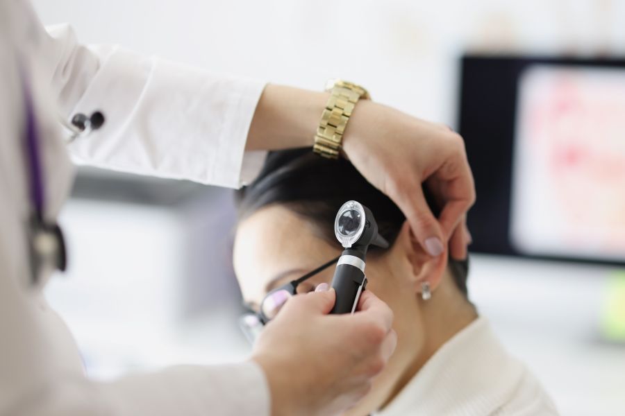 A Doctor is Examining a Woman's Ear With a Magnifying Glass — Clayton Hearing in Pialba, QLD
