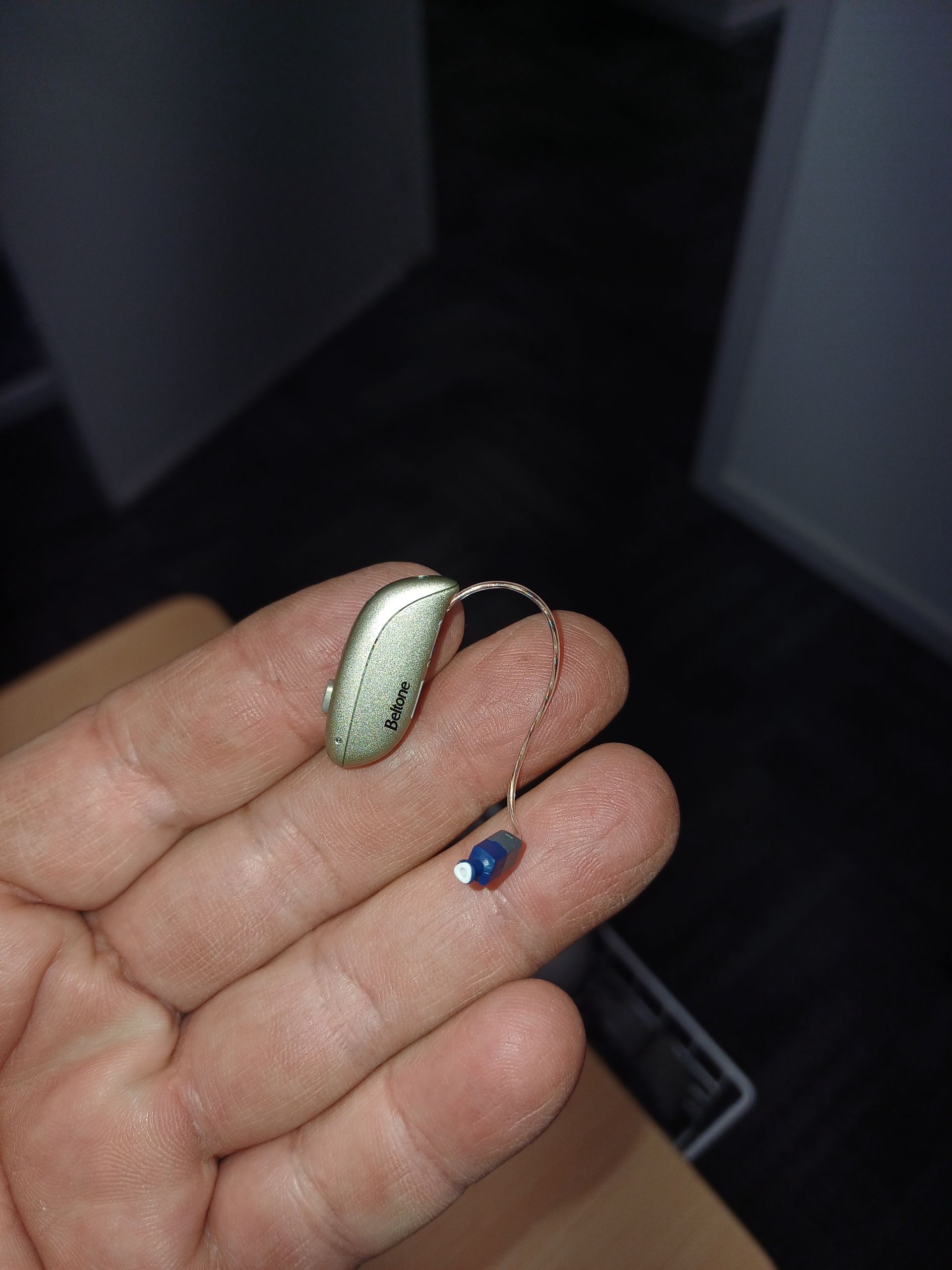 A Person is Holding a Hearing Aid in Their Hand — Clayton Hearing in Pialba, QLD