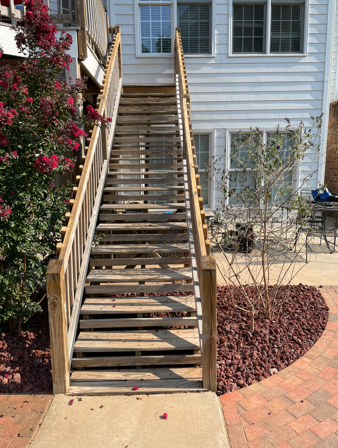 Wooden outdoor staircase with damaged steps, leading to a white building.
