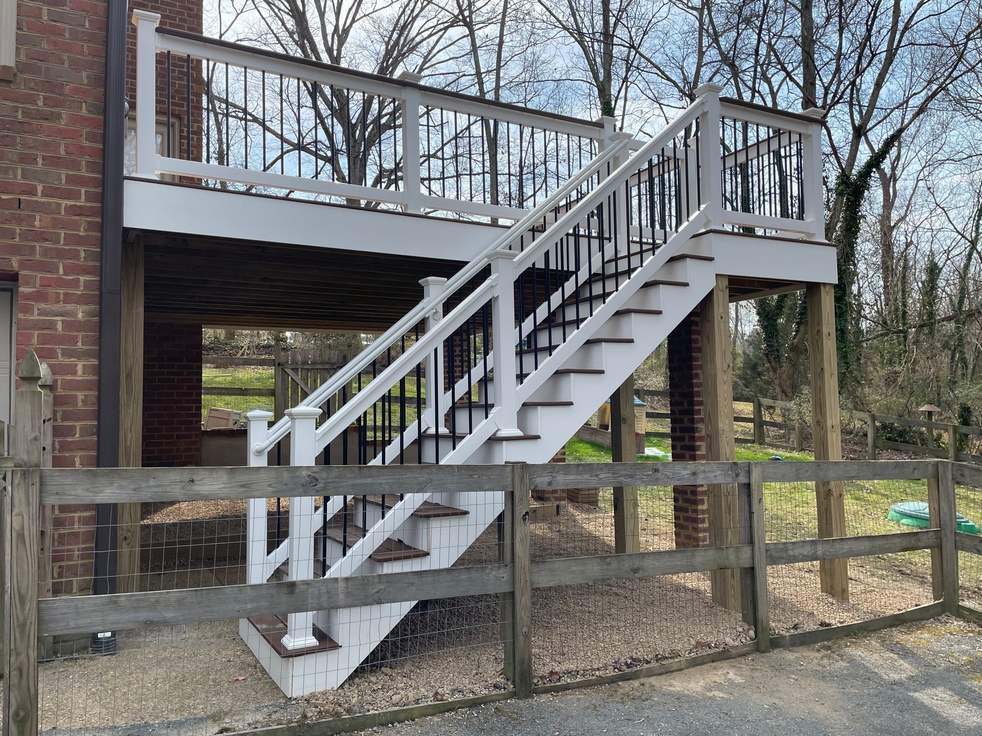 A white deck with stairs leading up to it and a wooden fence.