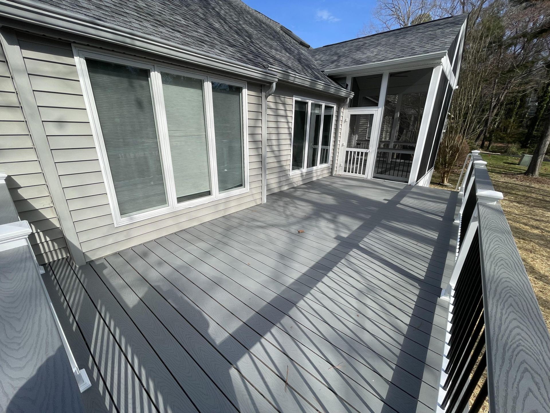 A large deck with a screened in porch in front of a house.