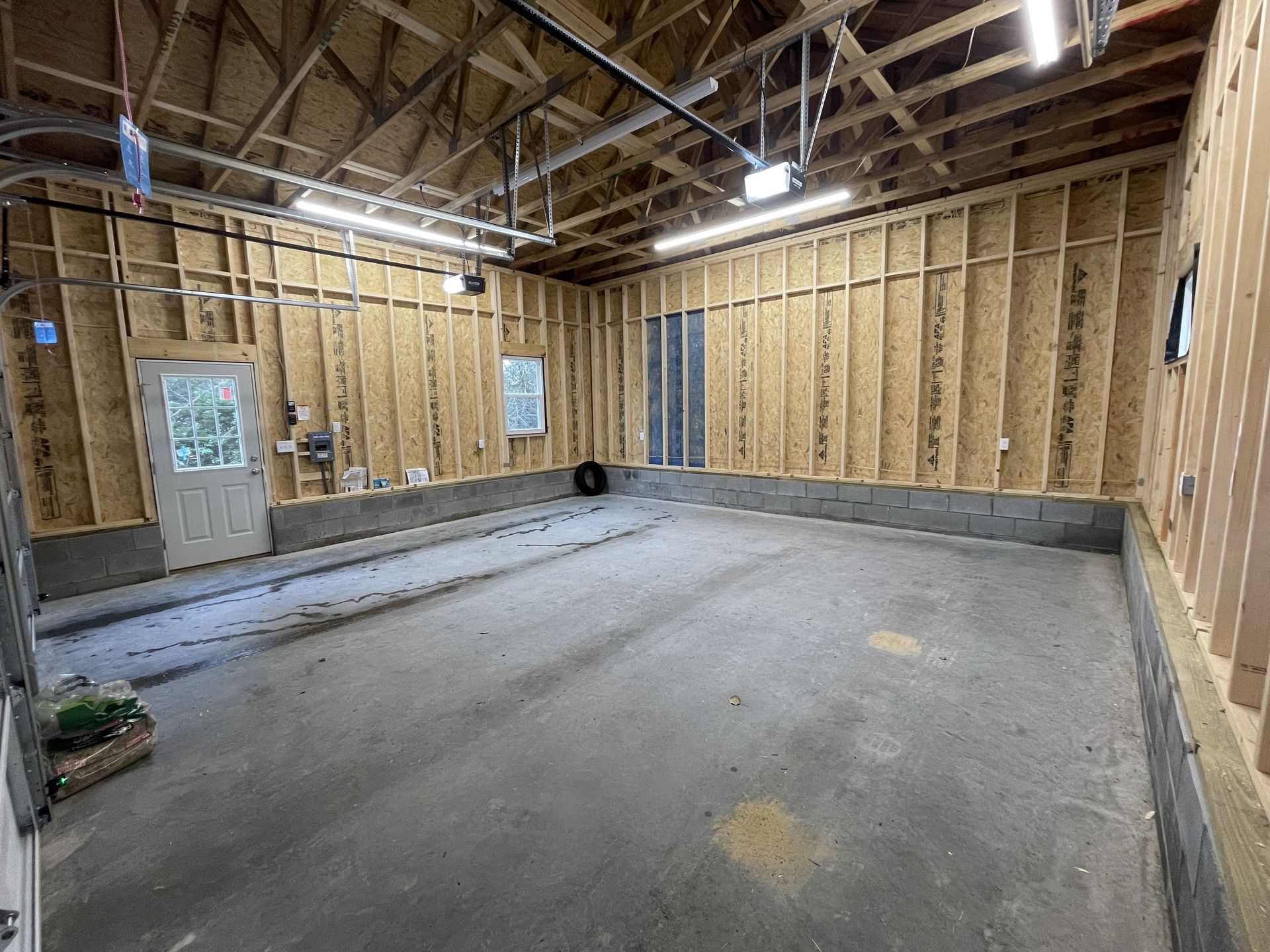 A large empty garage with a concrete floor and wooden walls.