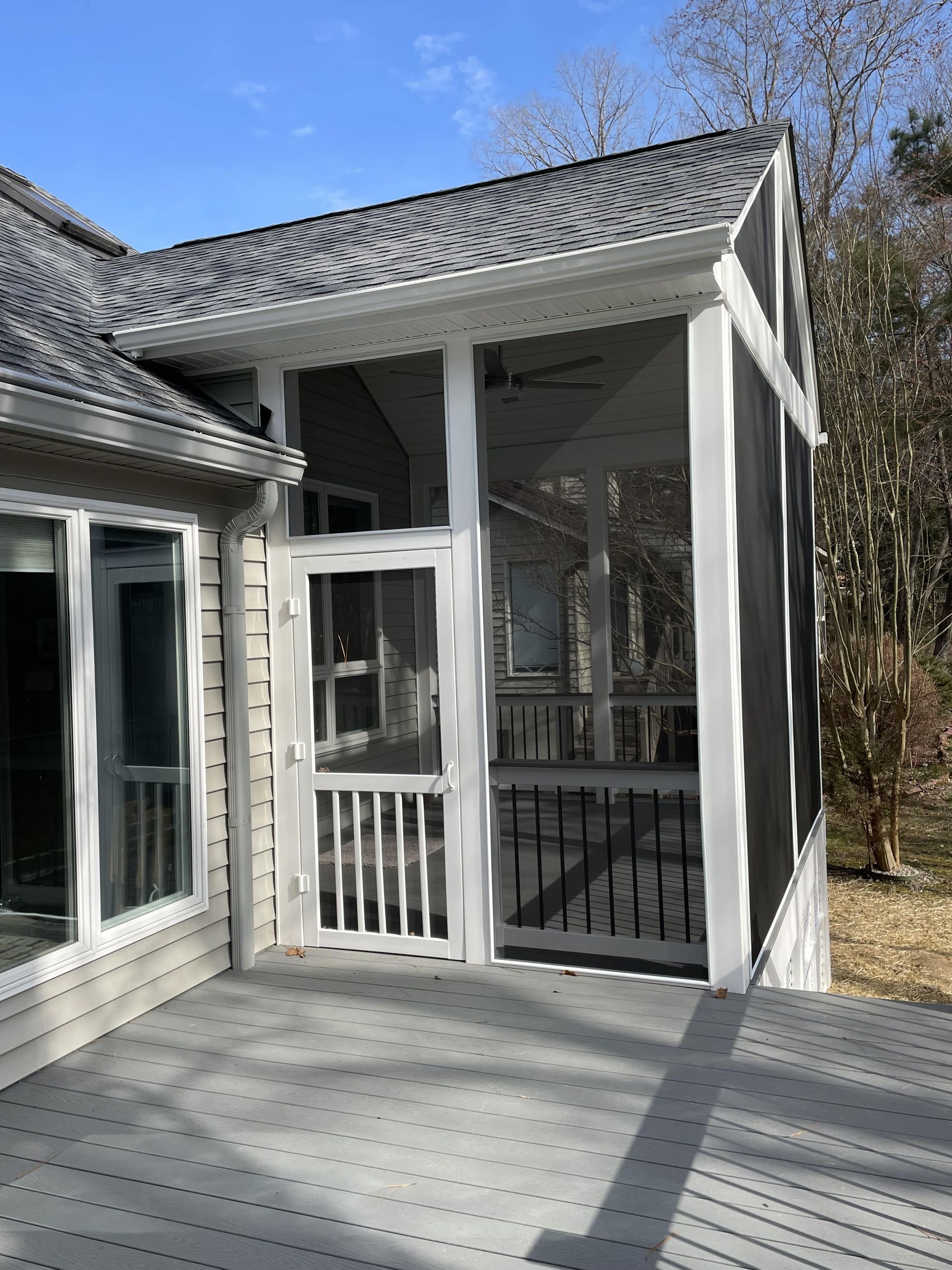 A screened in porch with a sliding glass door leading to a house.