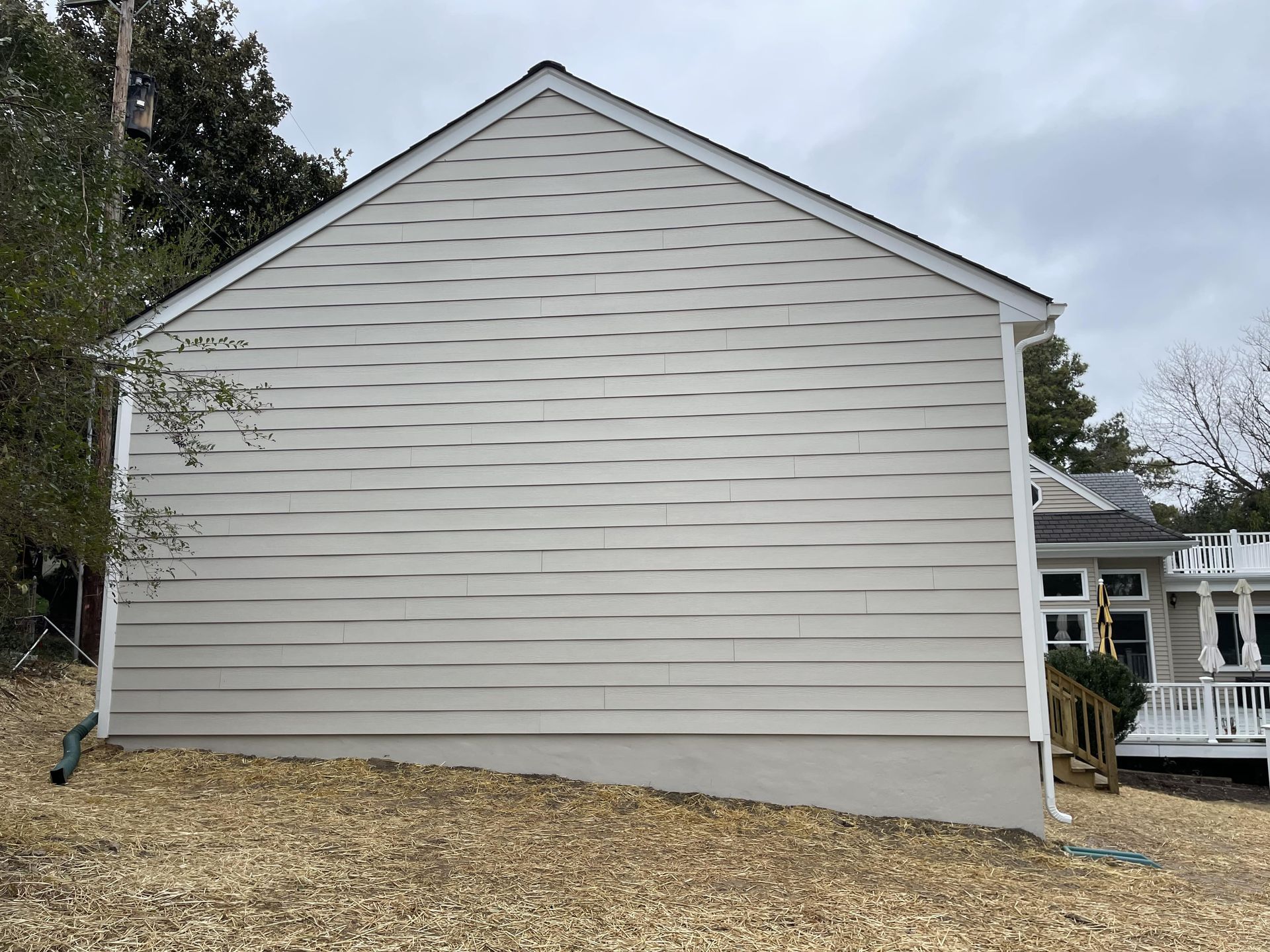 A white house with a black roof is sitting on top of a gravel hill.